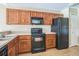 Well-lit kitchen features a black range, microwave and refrigerator, plus light wood cabinets at 2503 Se 18Th Cir, Ocala, FL 34471