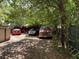 View of an overgrown backyard with various cars under an awning behind a few trees at 2520 Raehn St, Orlando, FL 32806