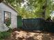 Overgrown backyard showing the side of a run-down house with a tarp-covered carport and a gate at 2520 Raehn St, Orlando, FL 32806