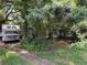 Exterior side view of home covered with mature trees and overgrown vegetation, and with RV parked beside it at 2520 Raehn St, Orlando, FL 32806