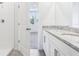 Bathroom with white cabinets, granite countertop, dual sinks, and tiled shower through an open door at 2774 Virginia Pine Dr, Bartow, FL 33830
