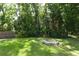 Beautiful backyard with mature trees, lush greenery, manicured lawn, fire pit and wooden fence at 304 Little Springs Ln, Longwood, FL 32750