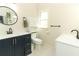 Bright bathroom featuring modern vanity with dark blue cabinets, a round mirror, and a toilet with storage at 304 Little Springs Ln, Longwood, FL 32750