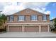 Three-story townhouse featuring three single-car garages and symmetrical window placement with shutters at 3416 Seneca Club Loop # 56, Orlando, FL 32808