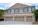 Exterior shot of a home featuring three garage doors and shuttered windows on the upper level at 3416 Seneca Club Loop # 56, Orlando, FL 32808