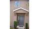 Close up of the unit's front door with grey paint, a covered porch, and small garden plants at 3416 Seneca Club Loop # 56, Orlando, FL 32808