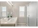 Bright bathroom featuring a double sink vanity, a large mirror, and a glass-enclosed shower at 386 Riggs Cir, Davenport, FL 33897
