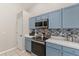 Well-lit kitchen featuring stainless steel appliances, light blue cabinets and a tiled backsplash at 386 Riggs Cir, Davenport, FL 33897
