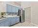 Well-lit kitchen featuring blue cabinetry, tile backsplash, and stainless steel refrigerator at 386 Riggs Cir, Davenport, FL 33897