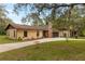 Single-story home exterior featuring stucco siding, brick chimney, mature trees, and two car garage at 4495 Bedford Rd, Sanford, FL 32773