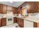 Compact kitchen with wood cabinets, white appliances, a window, and tile flooring at 4495 Bedford Rd, Sanford, FL 32773