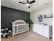Cozy Bedroom featuring a crib, a white dresser, unique wall decor, and a ceiling fan at 731 Rosemere Cir, Orlando, FL 32835
