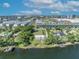 Aerial view of a lakefront house with a large lawn, mature trees, and city buildings in the distance at 7420 Lake Willis Dr, Orlando, FL 32821