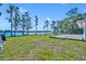 A spacious backyard with a wooden deck, beautiful lake views, and lush green grass on a sunny day at 7420 Lake Willis Dr, Orlando, FL 32821
