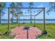 Brick fire pit area with pergola strung with lights near lake at 7420 Lake Willis Dr, Orlando, FL 32821