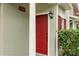 Close-up of a red front door with white trim and greenery at 10154 Regent Square Dr # 201, Orlando, FL 32825