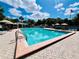Relaxing community pool with lounge chairs and umbrellas, surrounded by lush landscaping and an American flag waving in the distance at 1135 Marni Ridge Ct, Kissimmee, FL 34747