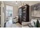 Elegant hallway featuring hardwood floors, neutral walls, a stylish display cabinet, and comfortable seating at 11725 Verrazano Dr, Orlando, FL 32836