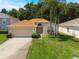 Charming single-story home featuring a well-maintained lawn, attached garage, and tropical palm trees at 122 Oak View Pl, Sanford, FL 32773