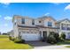 View of a two-story home with a manicured lawn, beautiful landscaping, and a two-car garage at 13090 Bromborough Dr, Orlando, FL 32832