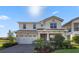 Two-story home with a manicured lawn, beautiful landscaping, and a two-car garage at 13090 Bromborough Dr, Orlando, FL 32832