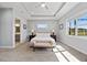 Spacious bedroom with tray ceiling, plush carpet, and large window for natural light at 13090 Bromborough Dr, Orlando, FL 32832