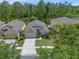 Aerial view of charming single-story home with a two-car garage, well-manicured lawn, and a lush, wooded backdrop at 14750 Hartford Run Dr, Orlando, FL 32828
