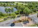 Aerial view of gated community entrance with palm trees, lush landscaping, and a serene lake backdrop at 14750 Hartford Run Dr, Orlando, FL 32828