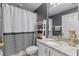 Well-lit bathroom with modern vanity, granite countertop, decorative shelving, and shower with stylish curtain at 14750 Hartford Run Dr, Orlando, FL 32828