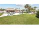 A well-manicured lawn and patio featuring an in-ground pool, spa, outdoor kitchen, and waterfront access at 151 Sea Isle Cir, South Daytona, FL 32119