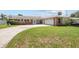 Charming one-story brick home featuring a well-manicured lawn and a long driveway leading to an attached garage at 151 Sea Isle Cir, South Daytona, FL 32119