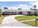 Well-kept brick house featuring a curved driveway, green lawn, and mature landscaping at 151 Sea Isle Cir, South Daytona, FL 32119