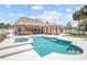 An in-ground pool, spa and outdoor kitchen with a thatched roof creates a backyard oasis at 151 Sea Isle Cir, South Daytona, FL 32119
