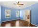 A sunny bedroom has blue walls, hardwood floors and a ceiling fan providing a comfortable and stylish space at 1516 Resolute St, Celebration, FL 34747