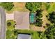 Aerial view of a home with a screened-in pool and a brick driveway surrounded by lush greenery at 24104 Peekskill St, Leesburg, FL 34748