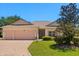 Inviting single-story home featuring a three-car garage and a beautifully manicured lawn under a clear blue sky at 24104 Peekskill St, Leesburg, FL 34748