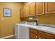 Practical laundry room with ample cabinet space, washer, dryer, and utility sink at 24104 Peekskill St, Leesburg, FL 34748