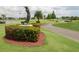 A golf course scene with a statue, red flowers, and a winding cart path under a cloudy sky at 3221 Westridge Blvd # 103, Orlando, FL 32822