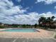 Community pool with brick perimeter, lake view, and pergola in the background at 3702 Palm Desert Ln # 5435, Orlando, FL 32839