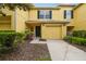 Charming yellow townhouse featuring an attached garage, well-manicured landscaping, and a welcoming front entrance at 3759 Collingwood Ln, Oviedo, FL 32765