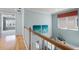 Bright hallway with wooden floors and railing overlooking downstairs, decorated with blue artwork, offers an open design at 5711 Hamlin Groves Trl, Winter Garden, FL 34787