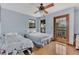 Light-filled bedroom featuring hardwood floors, ceiling fan, and access to a private outdoor balcony at 9222 Charles E Limpus Rd, Orlando, FL 32836