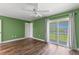 Spacious bedroom with green walls, wood floors, ceiling fan, and sliding glass doors to the balcony at 1152 Grove St, Maitland, FL 32751
