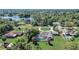 Aerial view of screened pool, lush backyard, circular driveway, and lake beyond at 1155 Collins Ave, Orange City, FL 32763