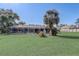 Spacious backyard with well-kept lawn, mature palm trees, and screened-in pool enclosure at 1155 Collins Ave, Orange City, FL 32763