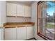 Butler pantry boasts custom cabinets and a view to the outdoors through a bright window at 1155 Collins Ave, Orange City, FL 32763