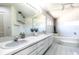 Bright bathroom featuring double sinks, a large mirror, and a tiled bathtub with modern fixtures at 117 Orange Ridge Dr, Longwood, FL 32779