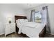 Cozy bedroom with a wooden bed frame, white bedding, and a window view at 15532 Kensington Trl, Clermont, FL 34711