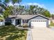 Charming single-story home with a well-manicured lawn, gray exterior and a two car garage at 15532 Kensington Trl, Clermont, FL 34711