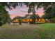 Expansive backyard at sunset, featuring lush landscaping, a patio, playground, and charming home exterior at 1555 Waterwitch Dr, Orlando, FL 32806